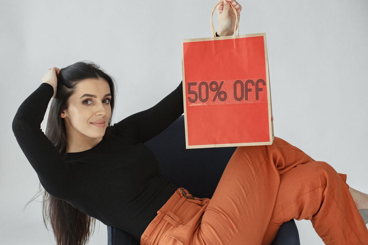 The Art of Drawing Readers In: Your attractive post title goes here Woman holding a vibrant 50% off shopping bag, promoting sales and discounts indoors.